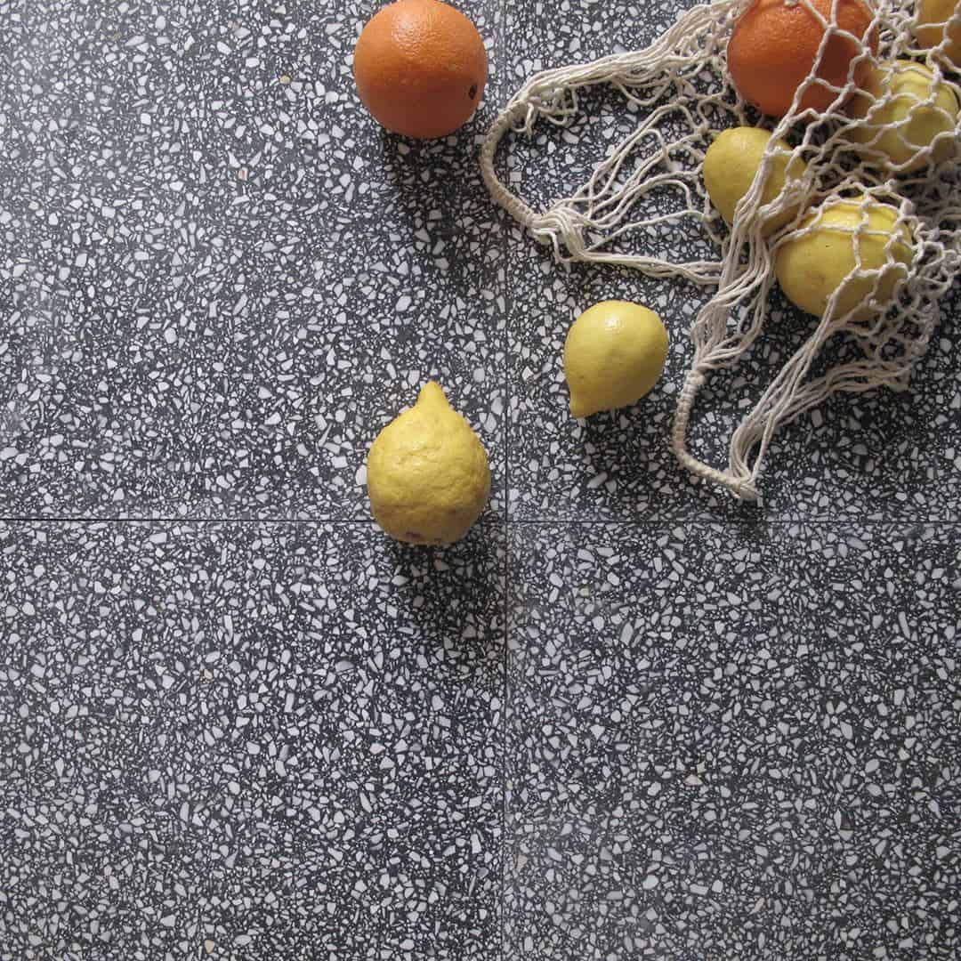 Dark terrazzo tile floor with scattered lemons, oranges, and a mesh produce bag in the corner.