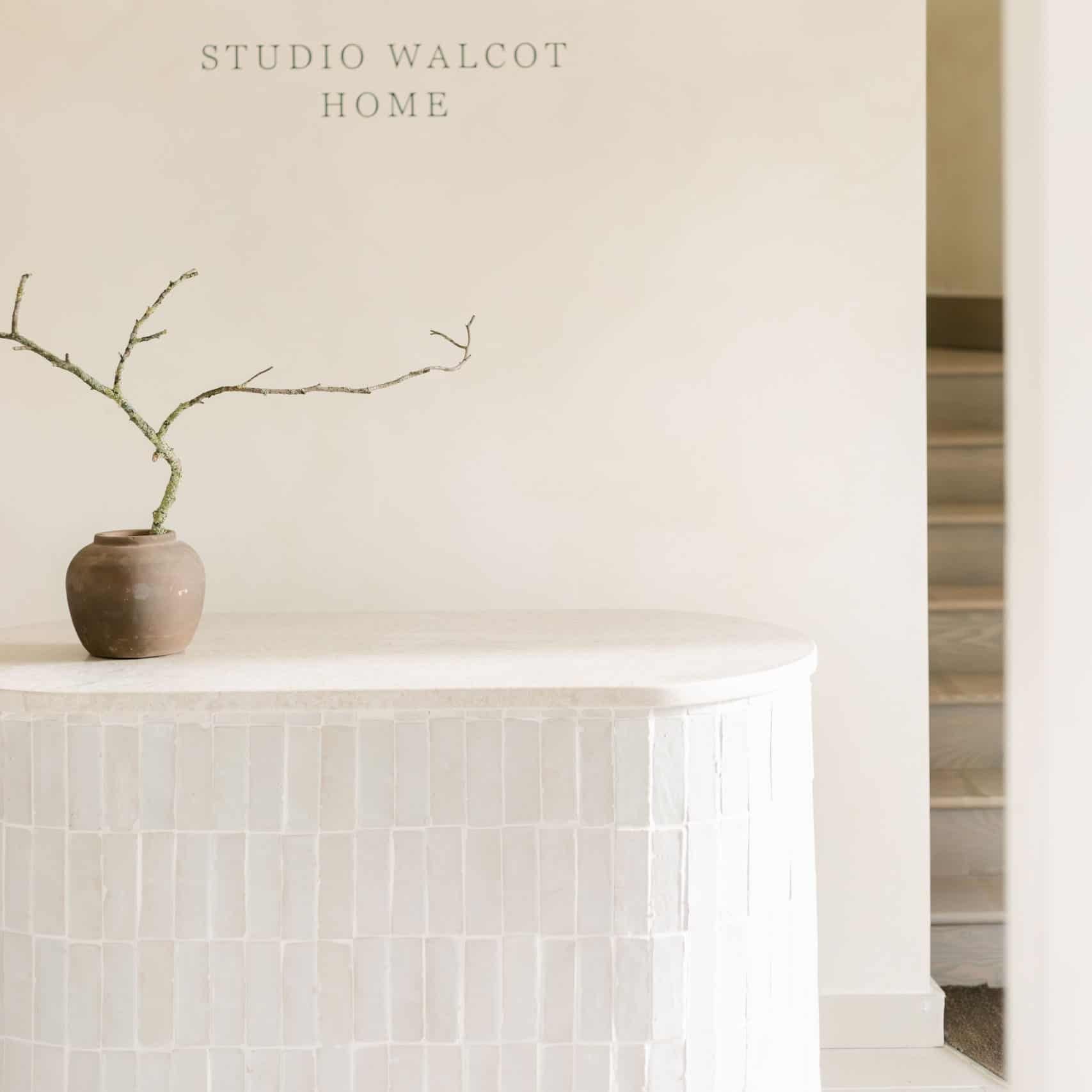 Minimalist interior with a vase on a shelf against a plain wall, featuring 'Studio Walcot Home' branding.