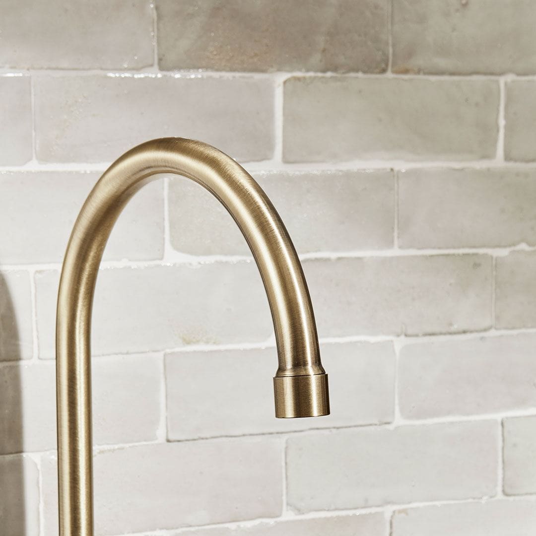Minimalist bathroom sink setup featuring a round stone basin with a brushed brass faucet.
