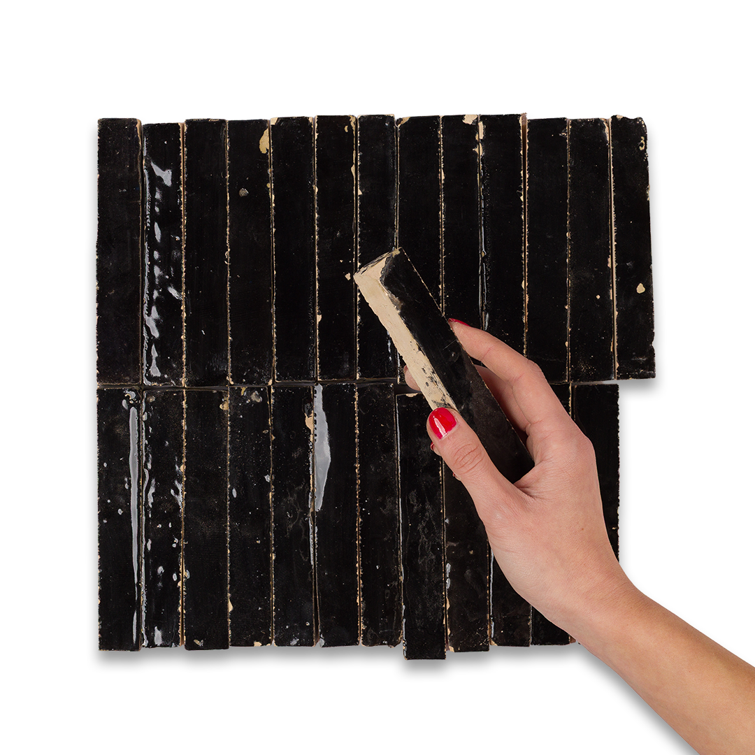 Hand holding a scrubber over a black tiled surface with visible wear.