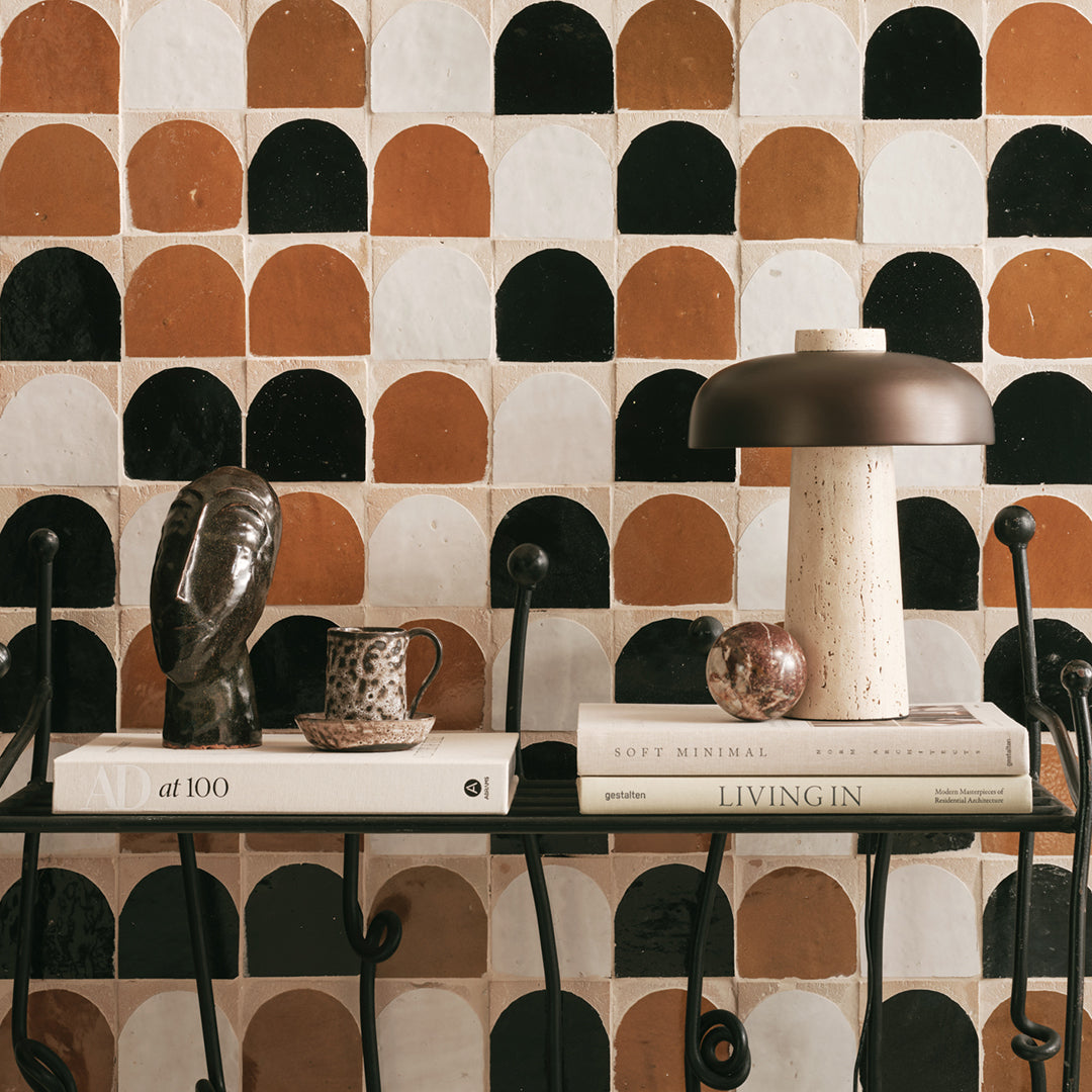 Decorative table with books and a lamp against a patterned wall.