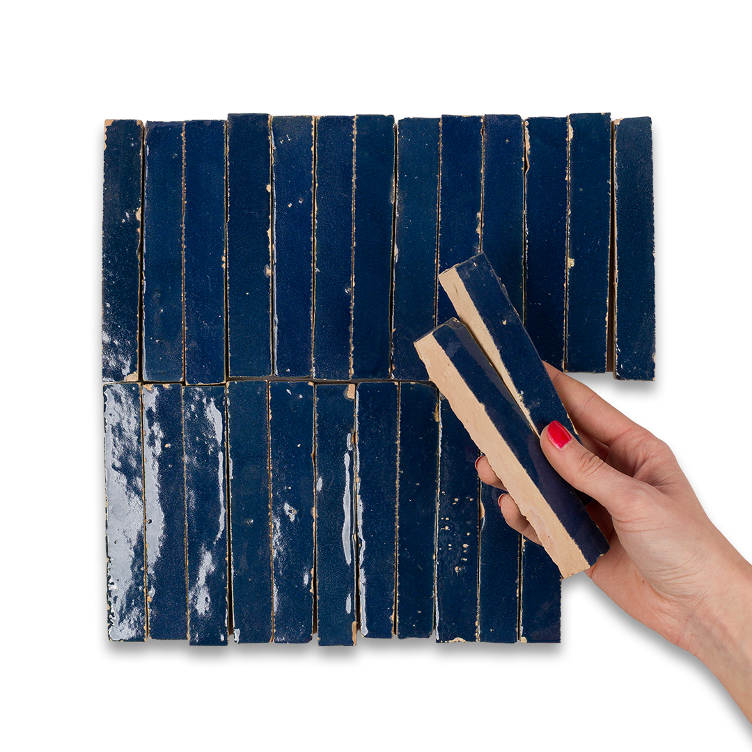 Hand holding a blue rectangular tile against a white background
