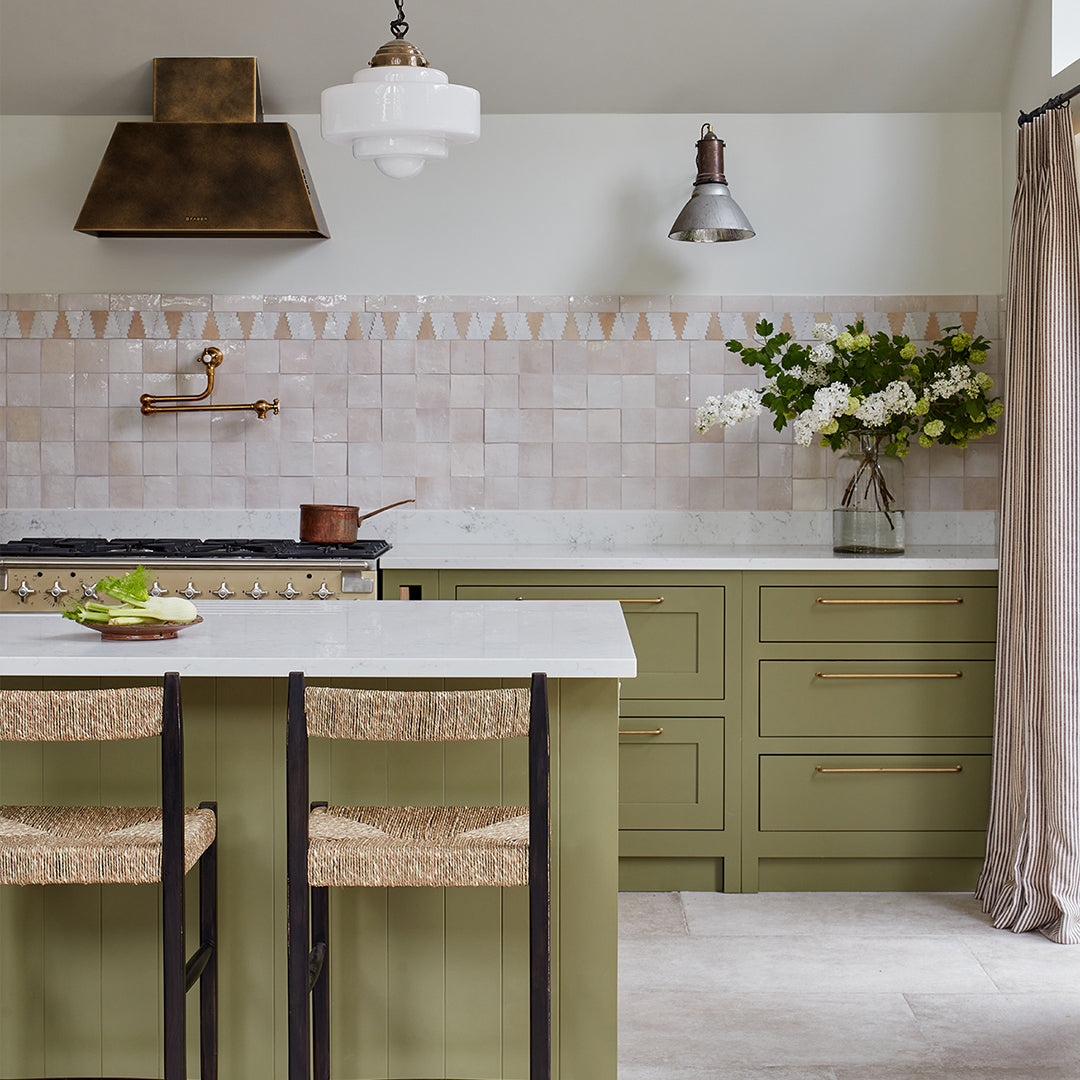 Modern kitchen with green cabinets, white countertops, and decorative elements.