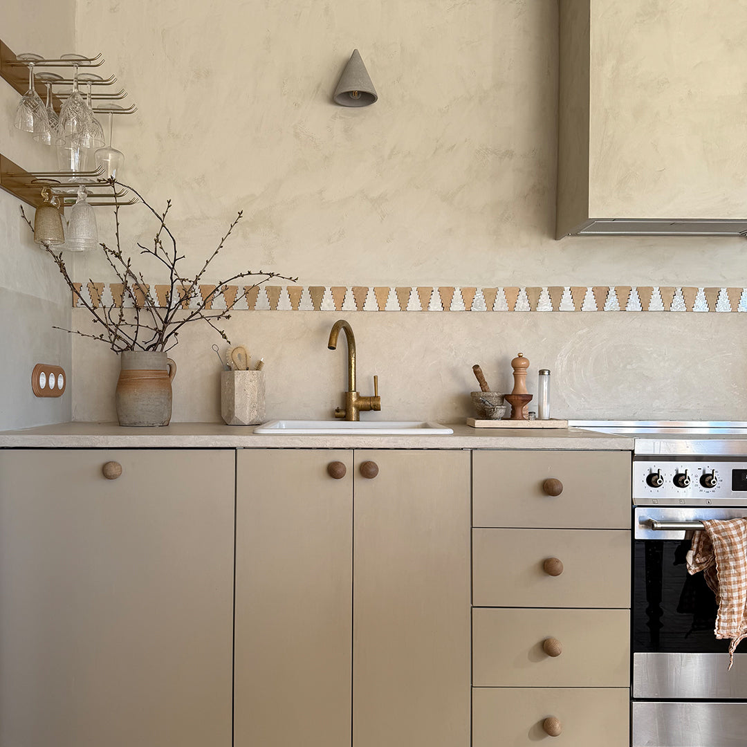 Modern kitchen with beige cabinets, stainless steel appliances, and decorative elements.
