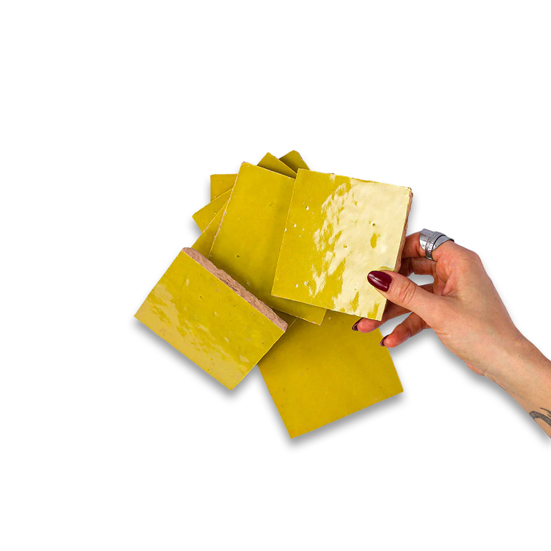 Hand holding a block of yellow cheese with more cheese slices on a white background