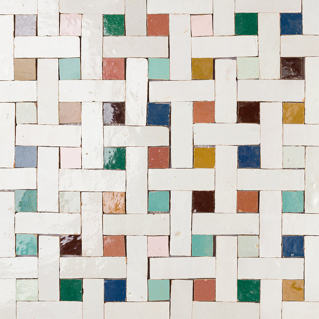Colorful woven-pattern tile floor made of white rectangular tiles interlaced with small squares in shades of teal, pink, yellow, brown, and green.