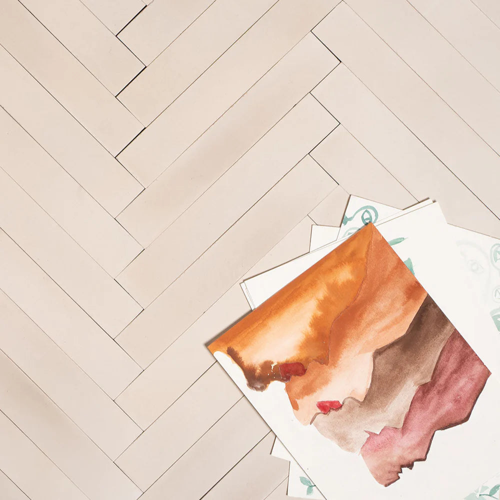 Cream-toned rectangular cement tiles arranged in a herringbone pattern, showcasing a smooth matte finish, ideal for modern interiors, minimalist flooring, and wall applications in contemporary spaces.