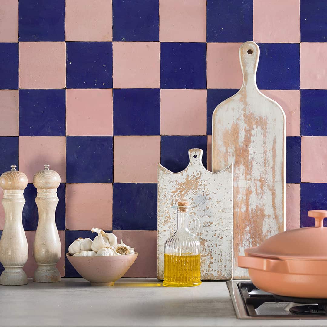 Cozy kitchen with checkered tile backsplash, garlic bowl, pepper mills, olive oil, and rustic cutting boards.