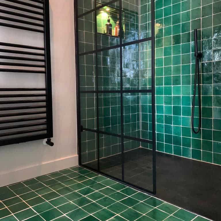 Luxurious bathroom green tiled walls, sink vanity, and an elegant mirror.