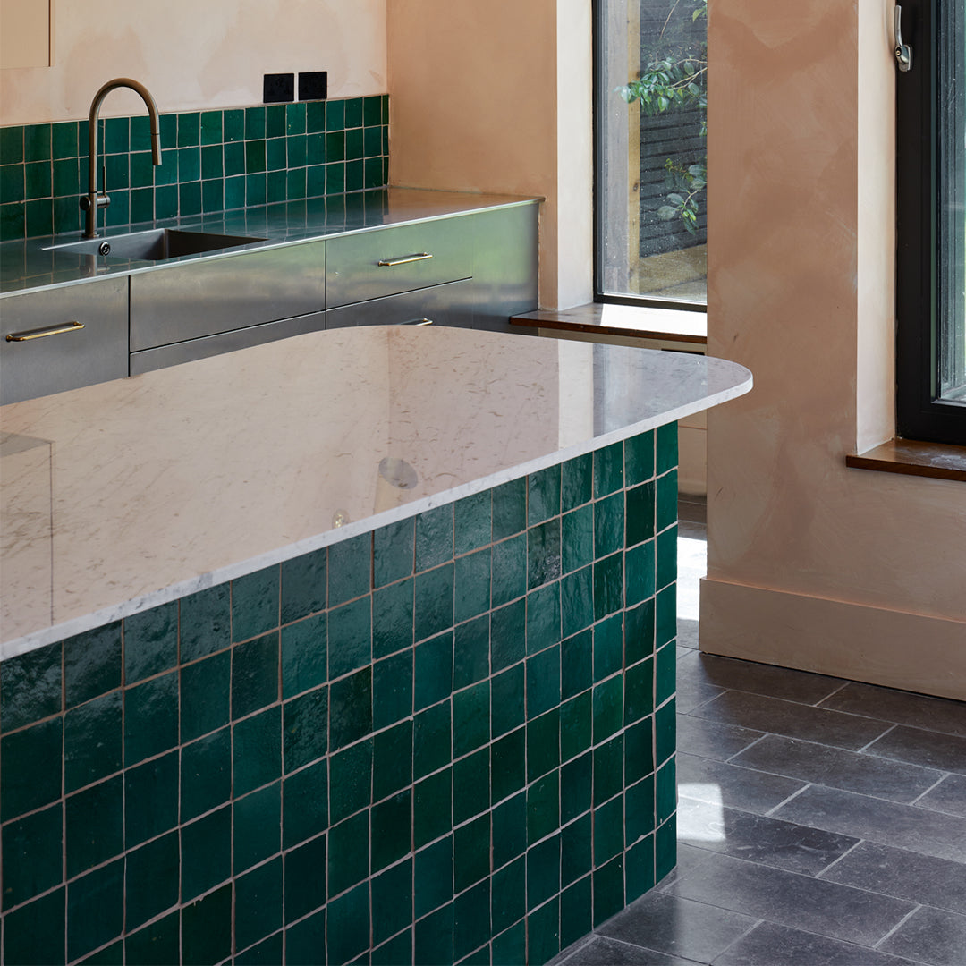 Modern kitchen with green tiled backsplash and marble island.