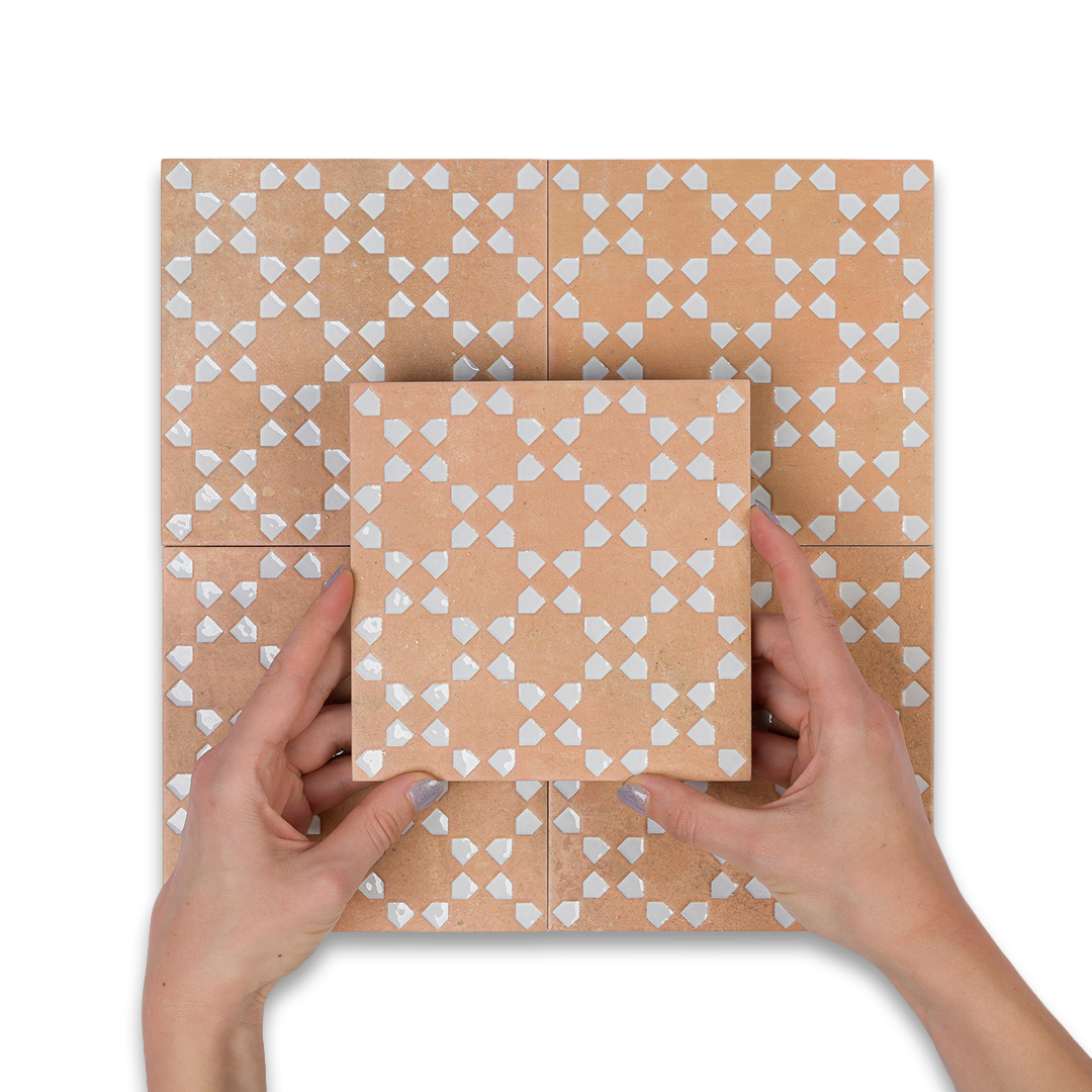 Hands holding a square piece of paper with a geometric pattern on a matching tiled background