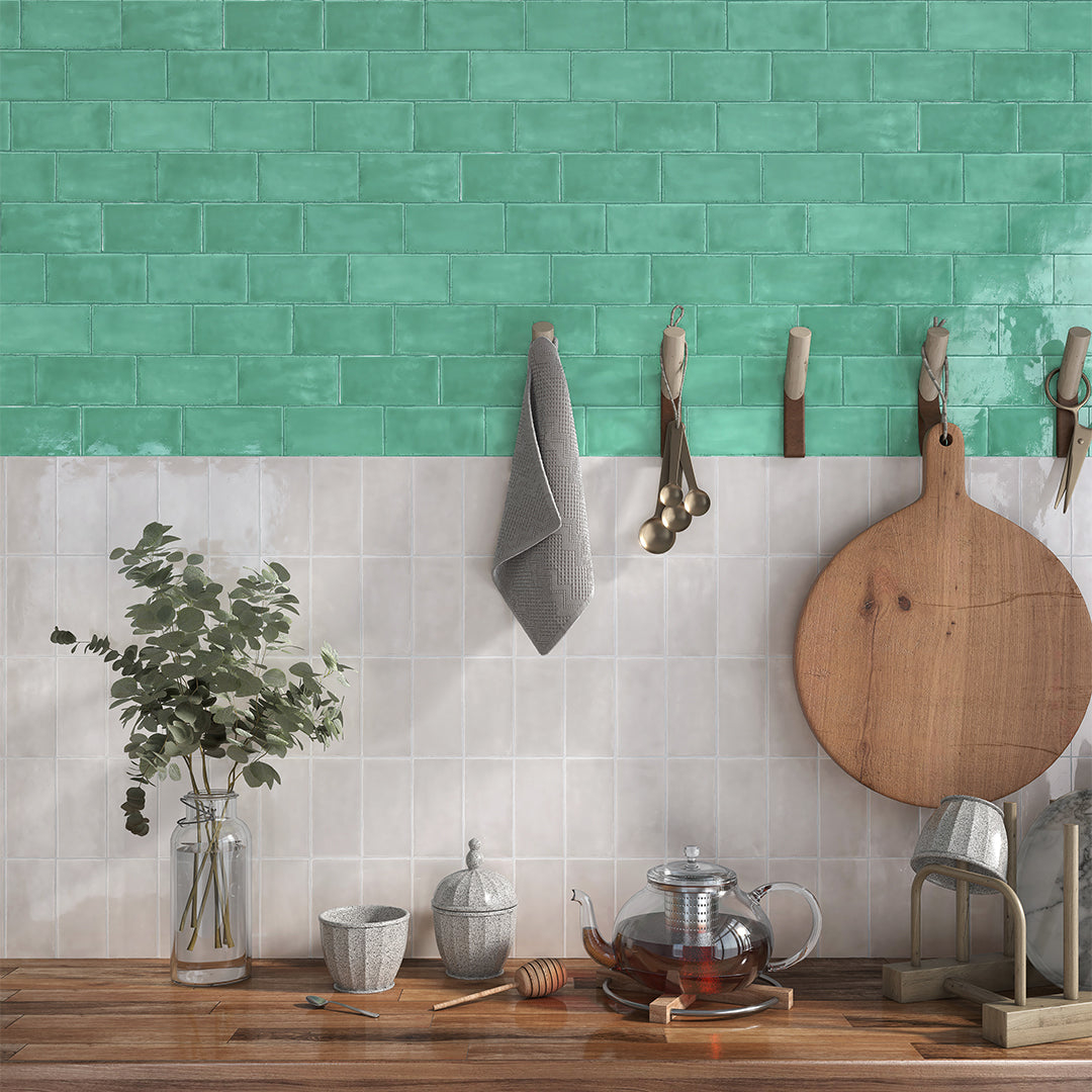 Kitchen counter with a teal tiled wall, wooden cutting board, and kitchen utensils.