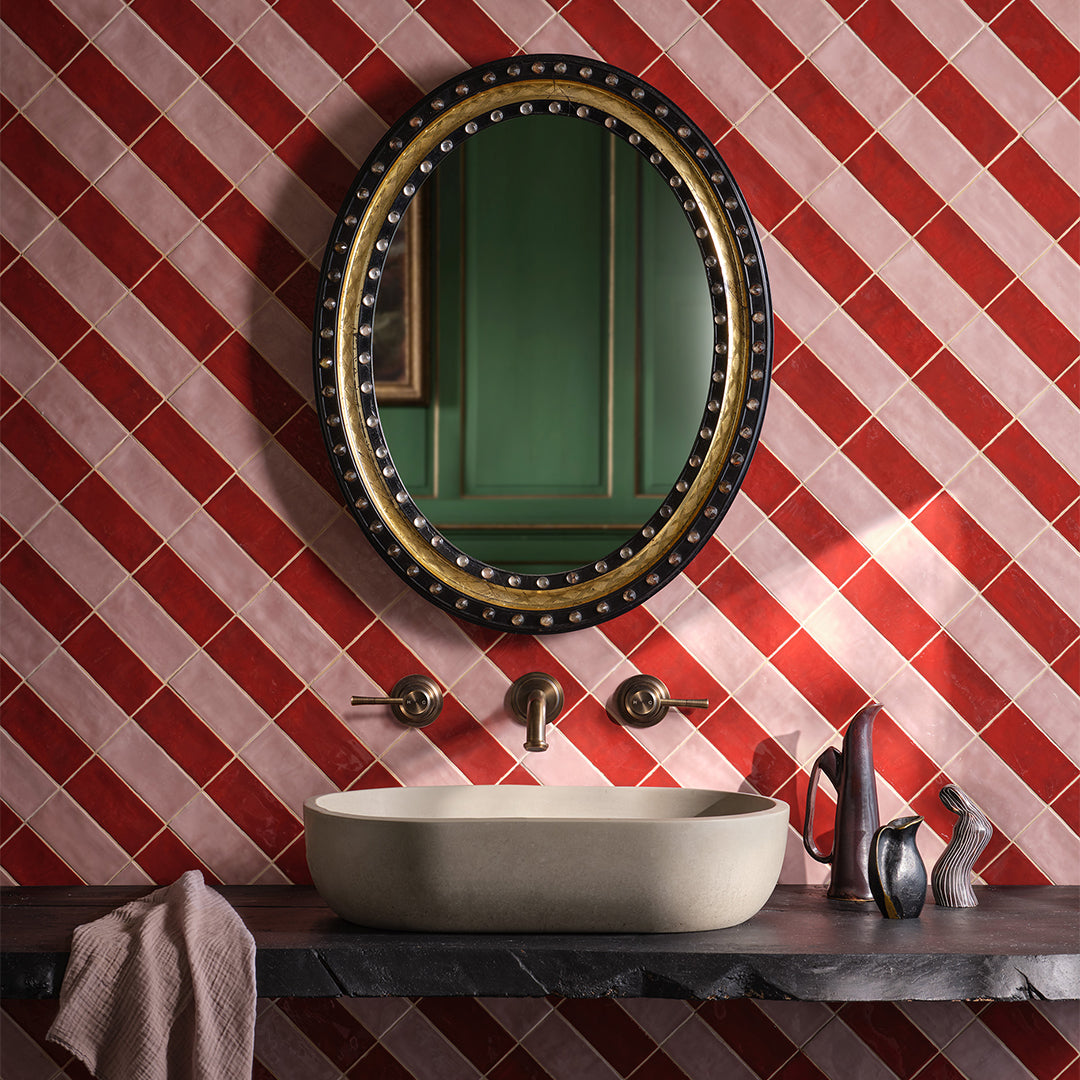 Bathroom with red and white tiled wall, round mirror, and sink.