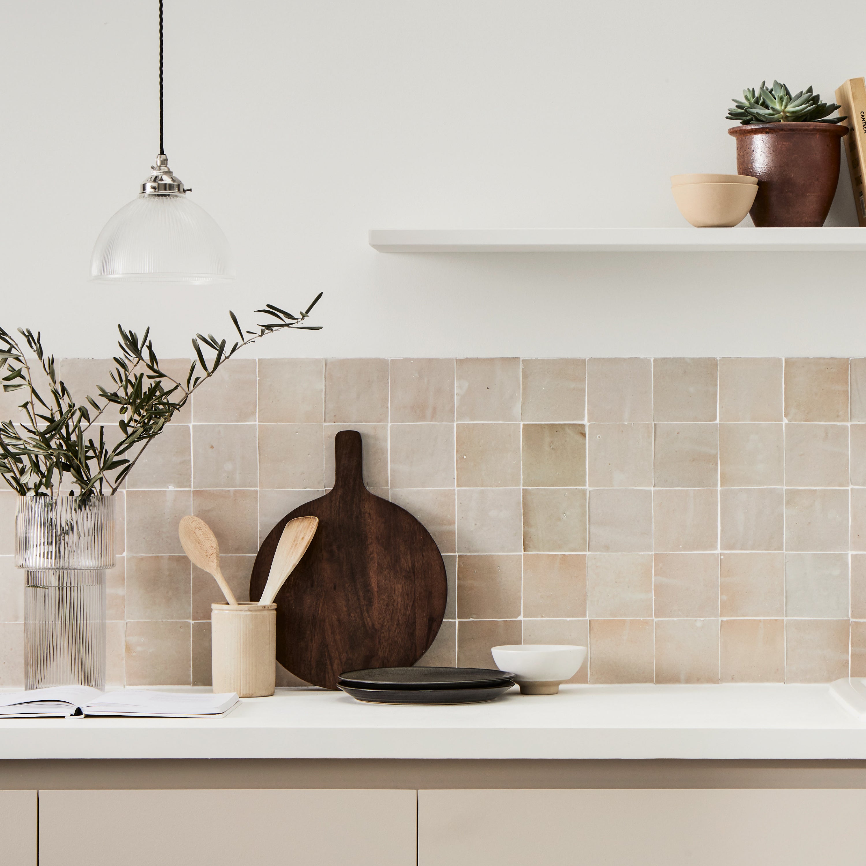 Modern kitchen with tiled backsplash, wooden cutting board, and decorative items.