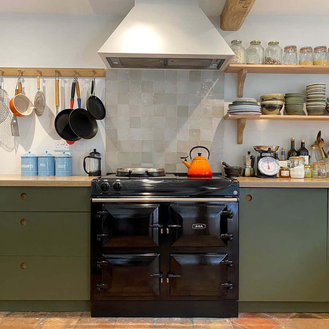A rustic kitchen interior with a wooden dining table and two chairs, a light yellow sideboard, and a floating wooden shelf above.