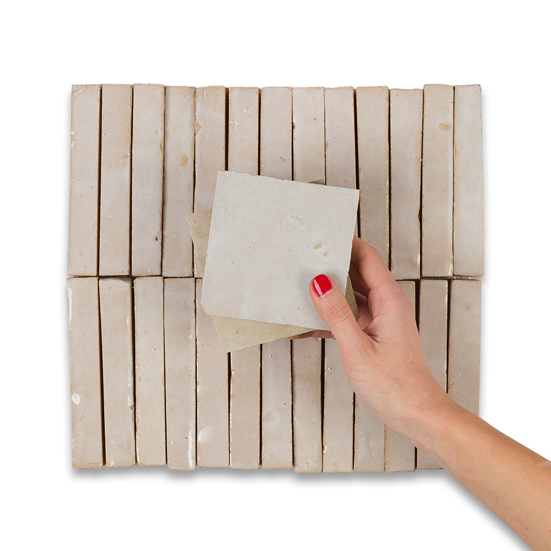 Hand holding a square piece of material over a woven mat on a white background