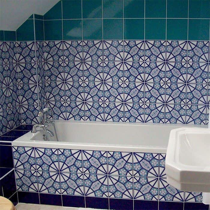 Bathroom with blue patterned wall tiles, white bathtub, and geometric mosaic tile design.