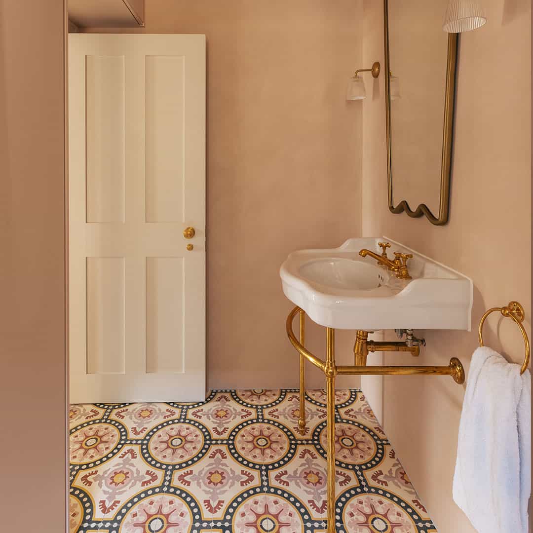 Bathroom with white sink, gold fixtures, and patterned floor tiles.