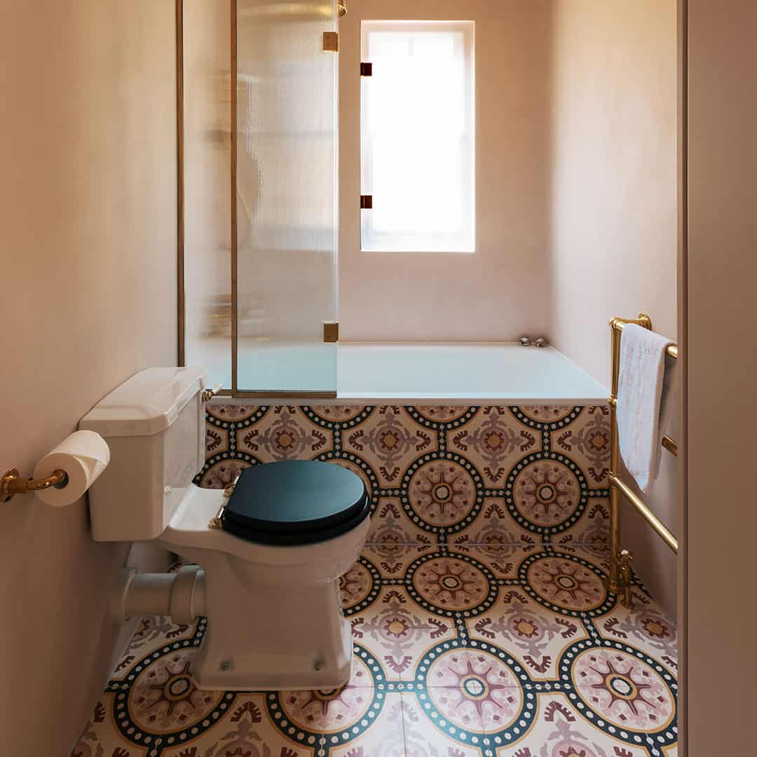 Bathroom with patterned tiles, toilet, and bathtub.