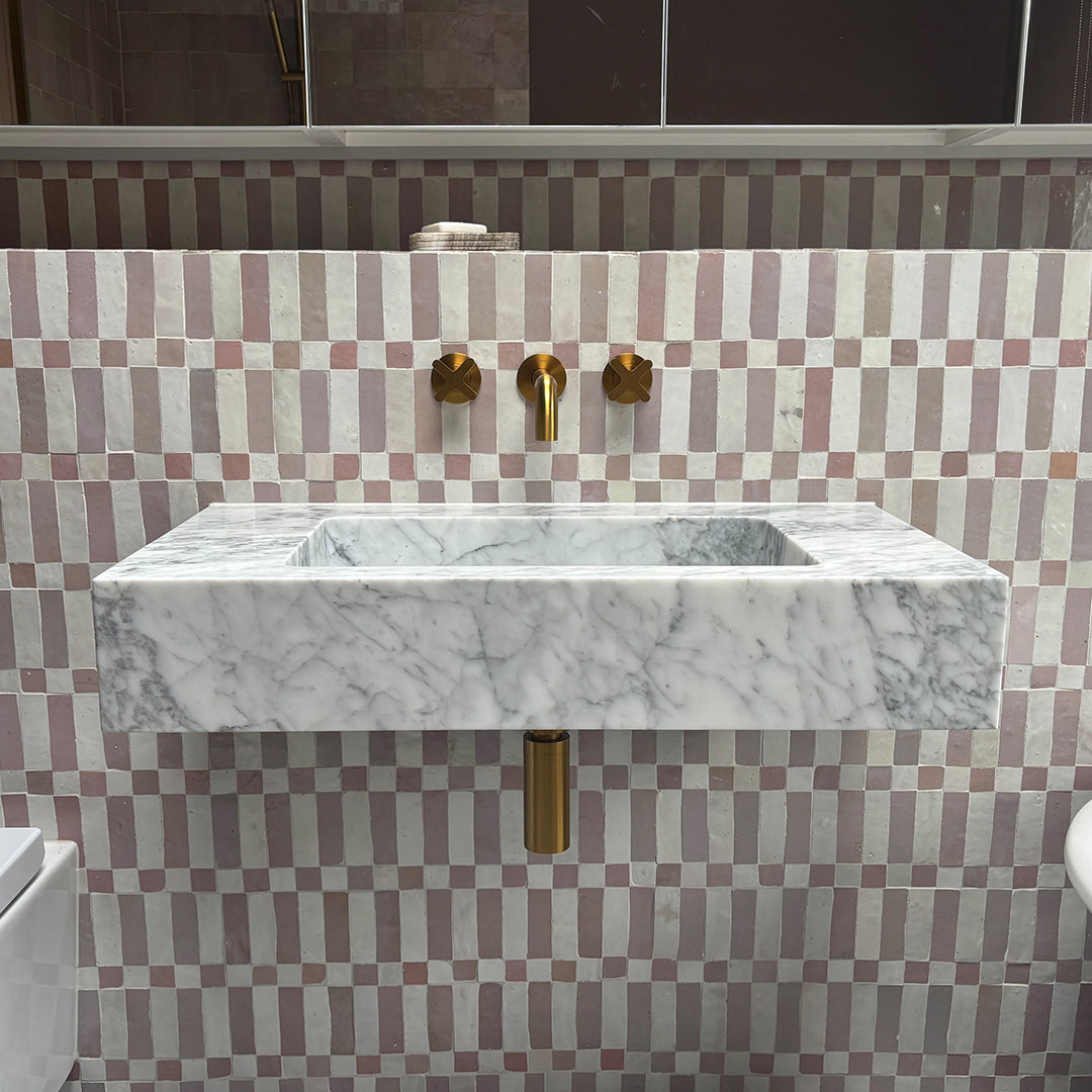Marble sink with gold fixtures against a checkered wall