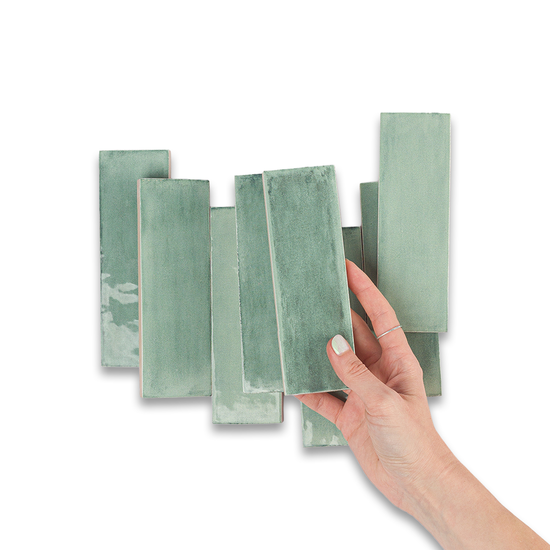Set of green ceramic tiles with a hand holding one tile against a white background
