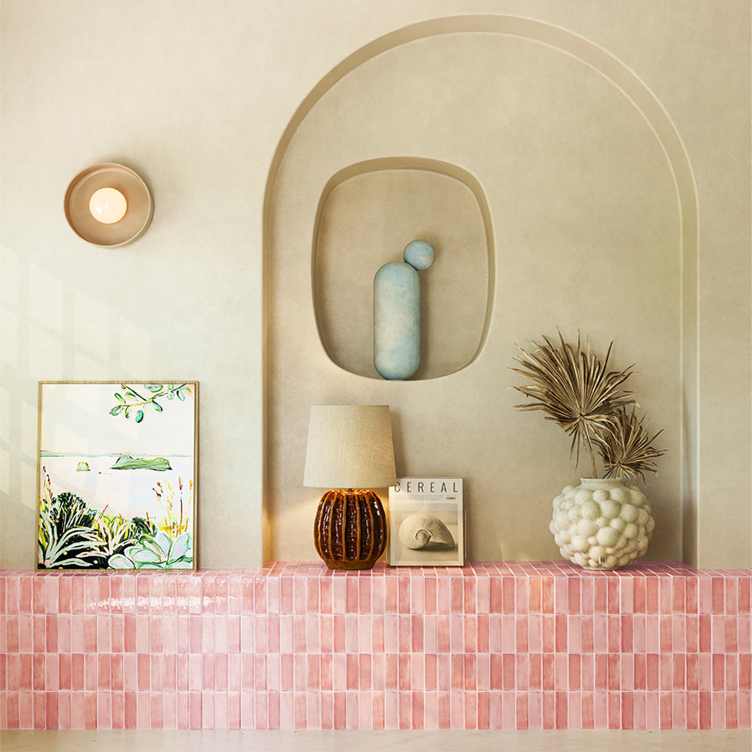 Decorative shelf with a lamp, vase, and framed picture against a beige wall.