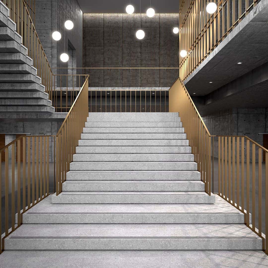 Modern staircase with light terrazzo steps, gold railings, concrete walls, and hanging globe pendant lights.