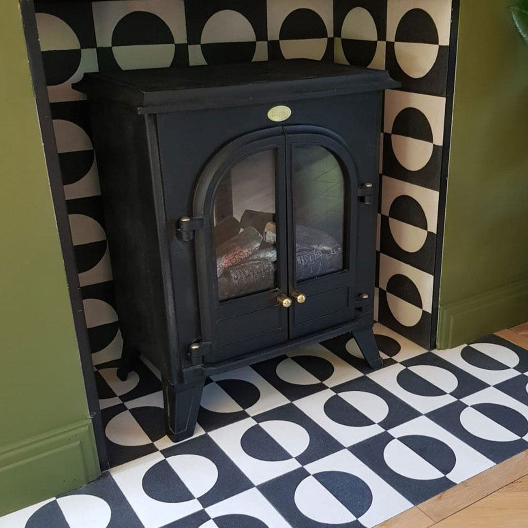 Black stove against black and white geometric cement tile featuring a bold circular half-moon pattern, minimalist modern design, matte finish, ideal for contemporary flooring, wall décor, and architectural interior applications.