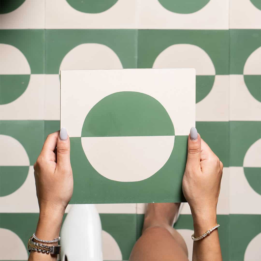 Square cement tile with minimalist geometric design, featuring mirrored beige and green semi-circles forming a bisected circle