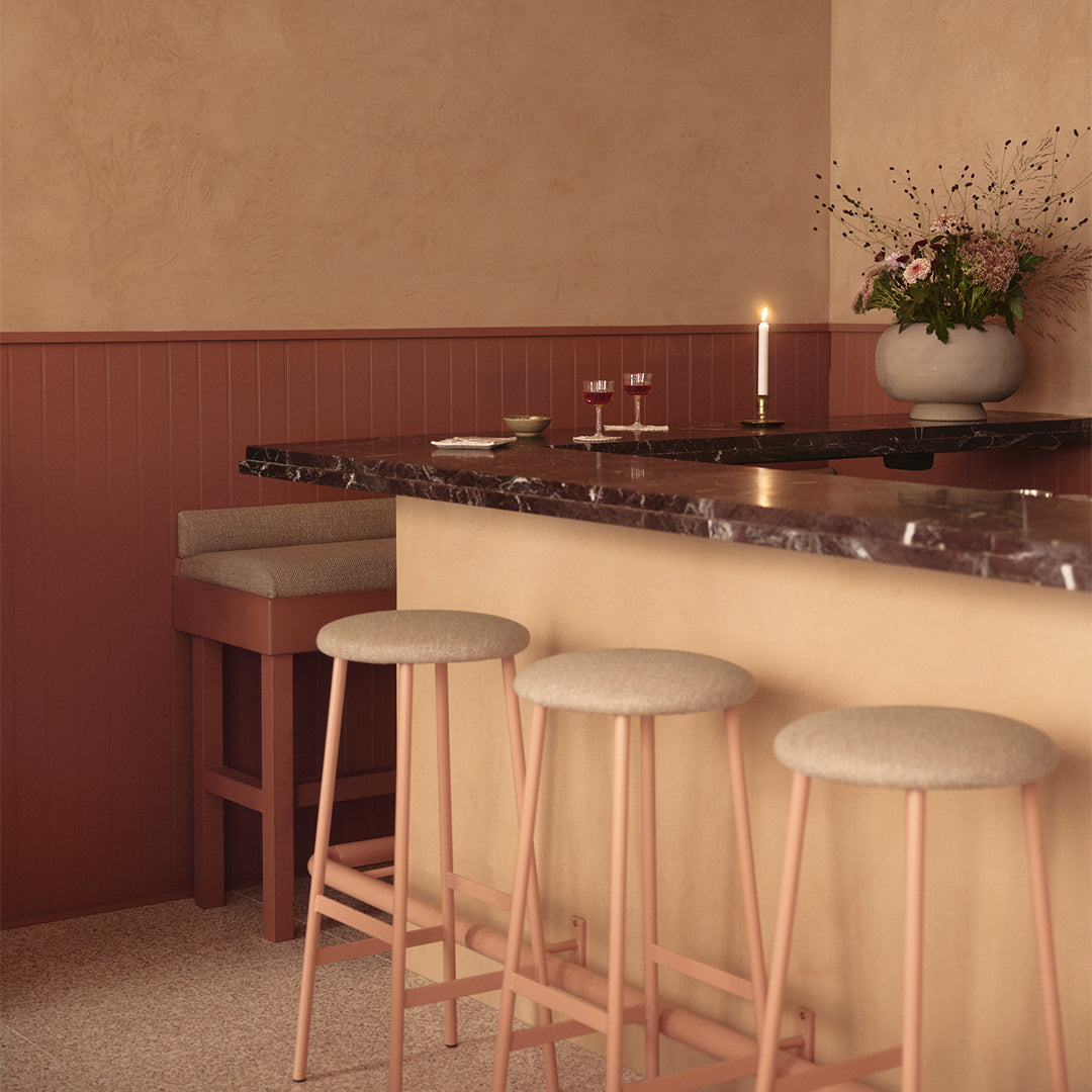 Bar area with stools, a counter, and decorative elements in a warm-toned room.