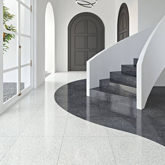 Minimalist interior with curved staircase, white walls, and contrasting black and white terrazzo flooring with a circular inlay.