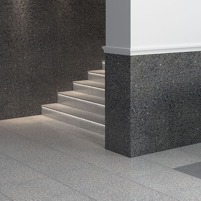 Minimalist interior with staircase, white walls, and contrasting grey and white terrazzo flooring.