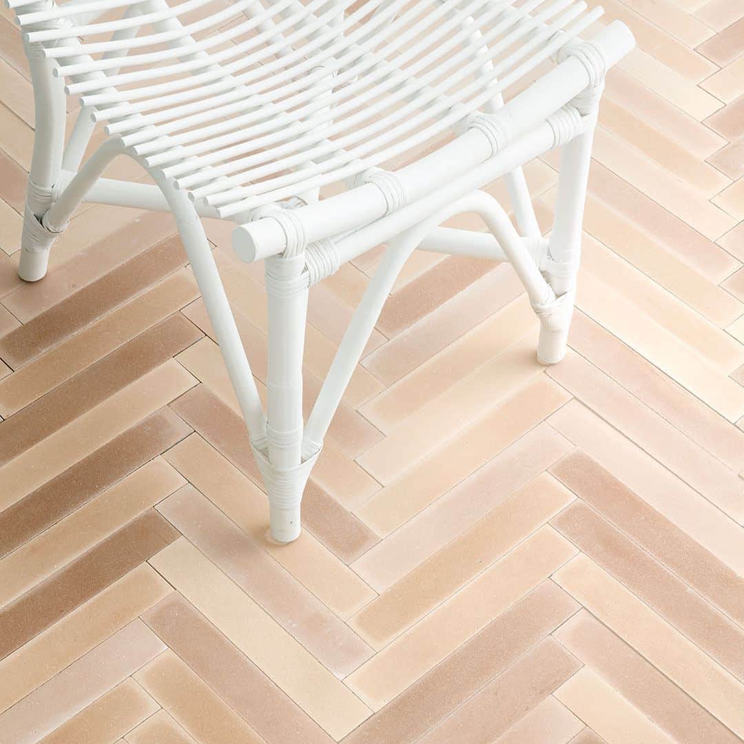 A rectangular blush pink tiles arranged in a herringbone pattern, matte finish, ideal for modern, Scandinavian, or minimalist flooring and wall décor applications.