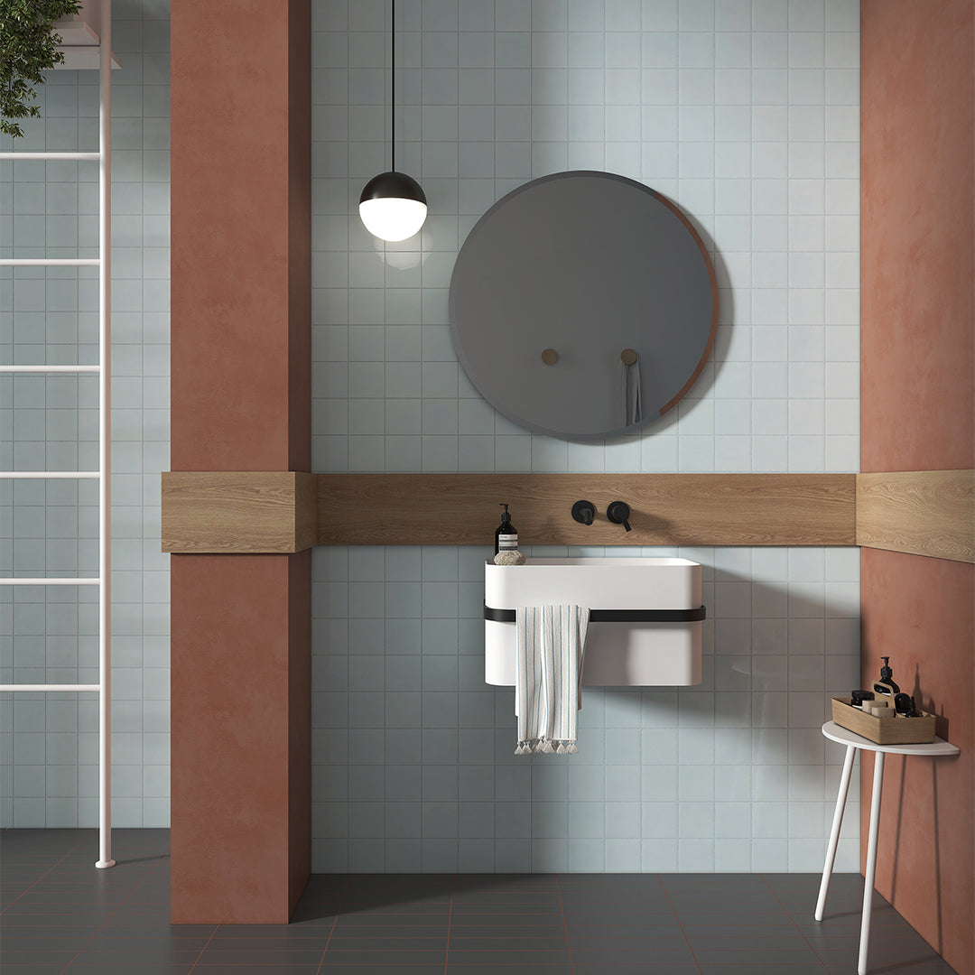 Bathroom with a round mirror, sink, and small table with items.