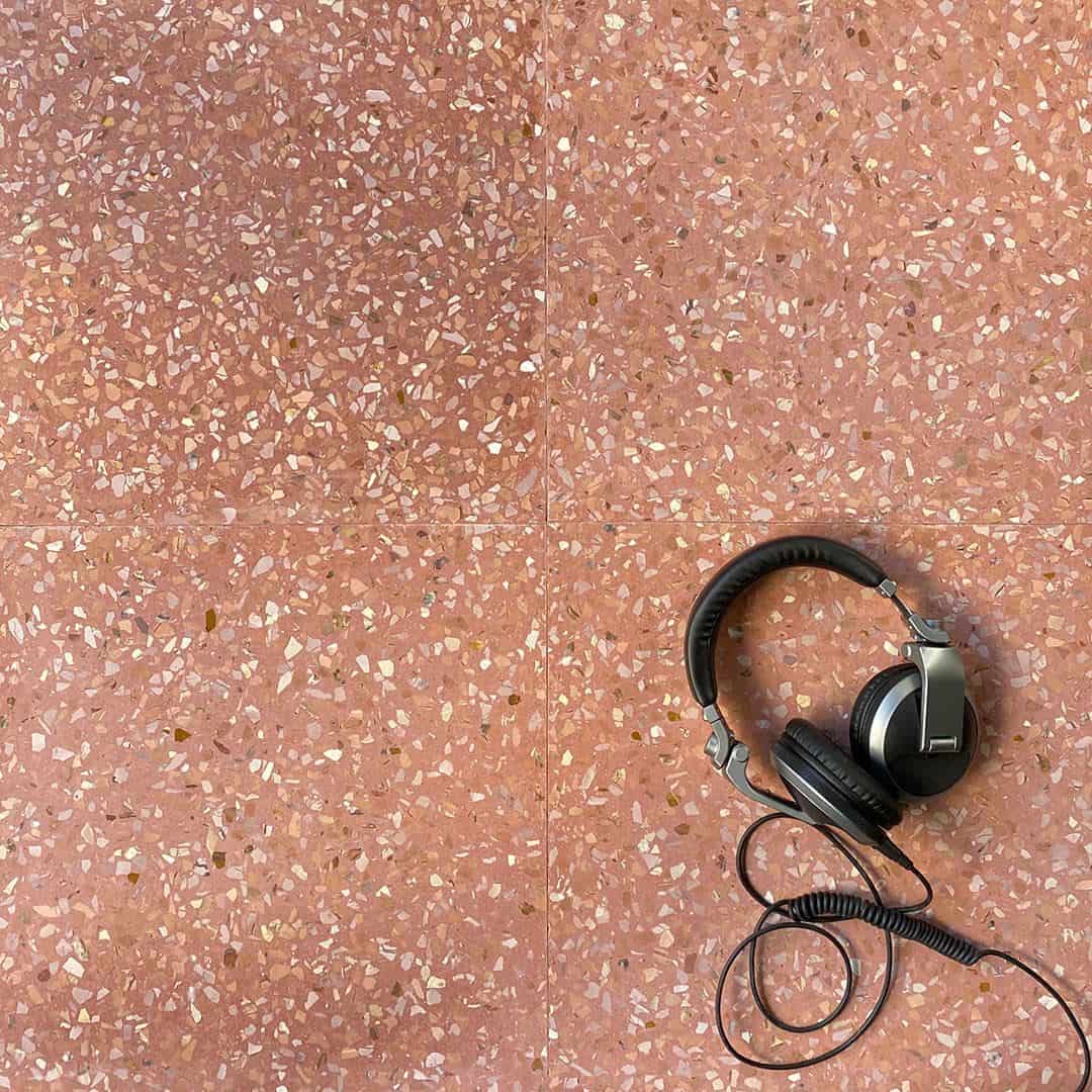 Terrazzo-style square tile with a pinkish-brown color and speckled pattern on a white background