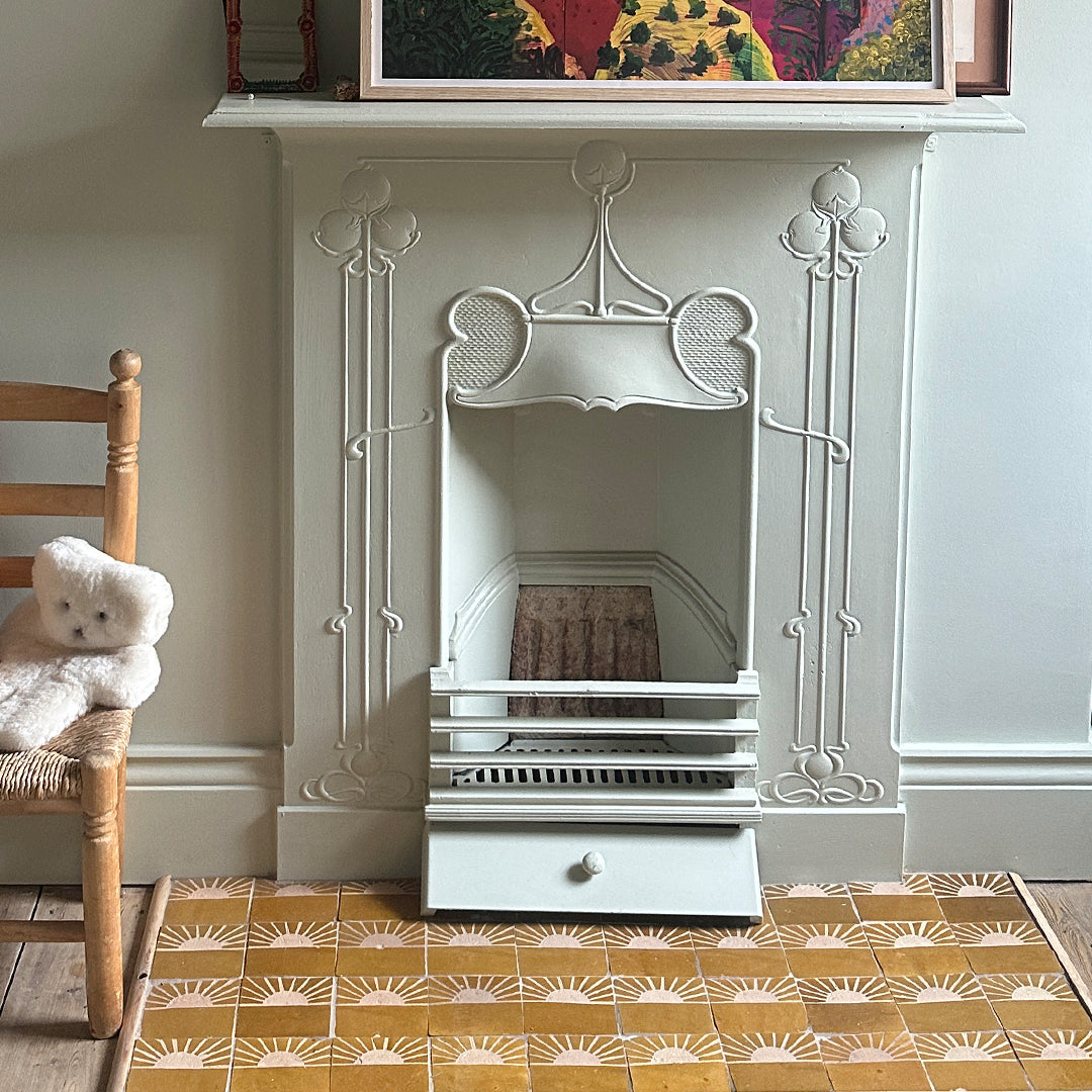 A decorative fireplace with an ornate Art Nouveau surround featuring floral and curved designs.