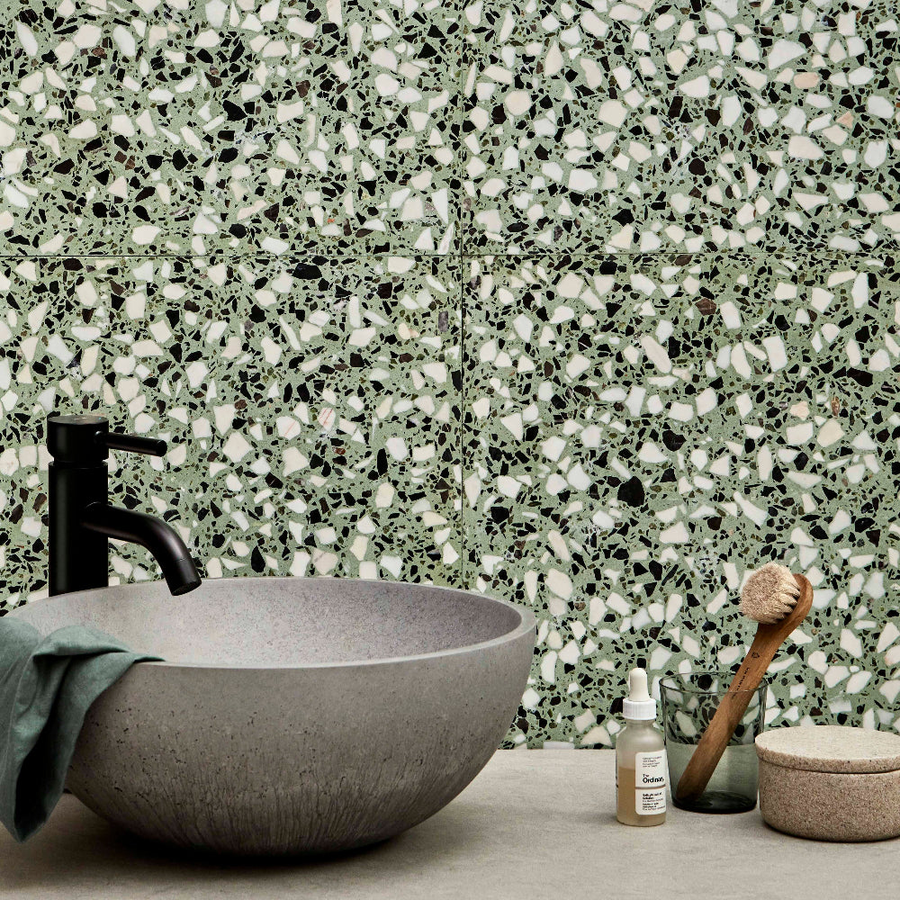Bathroom setting with a terrazzo-patterned wall, gray sink, and various bathroom items.