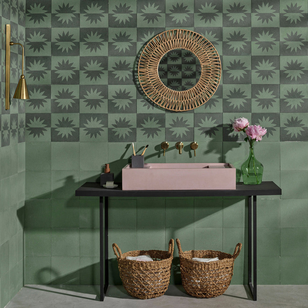 Square cement tile with symmetrical flower-like motif, mirrored across horizontal division in muted greenish-blue and beige, creating a modern minimalist design.