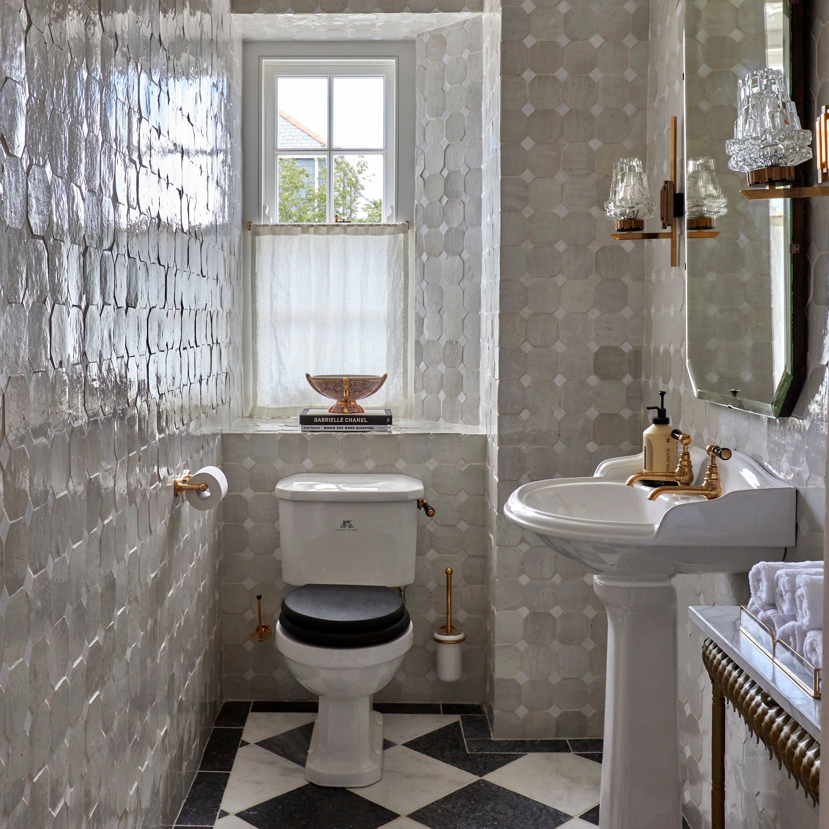 Bathroom with tiled walls, toilet, sink, and decorative elements.