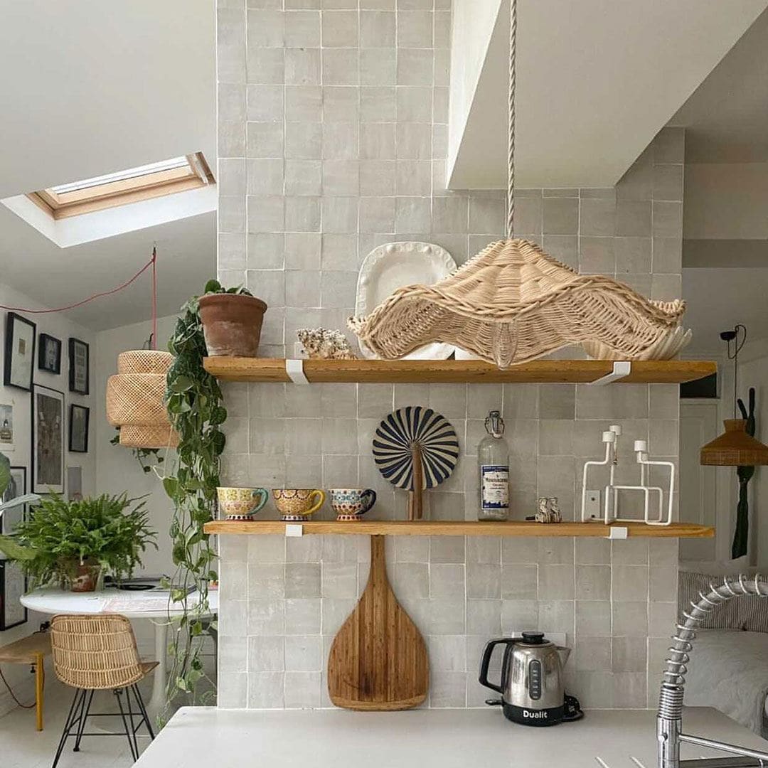 A cozy modern kitchen corner with two wooden shelves on a tiled wall.