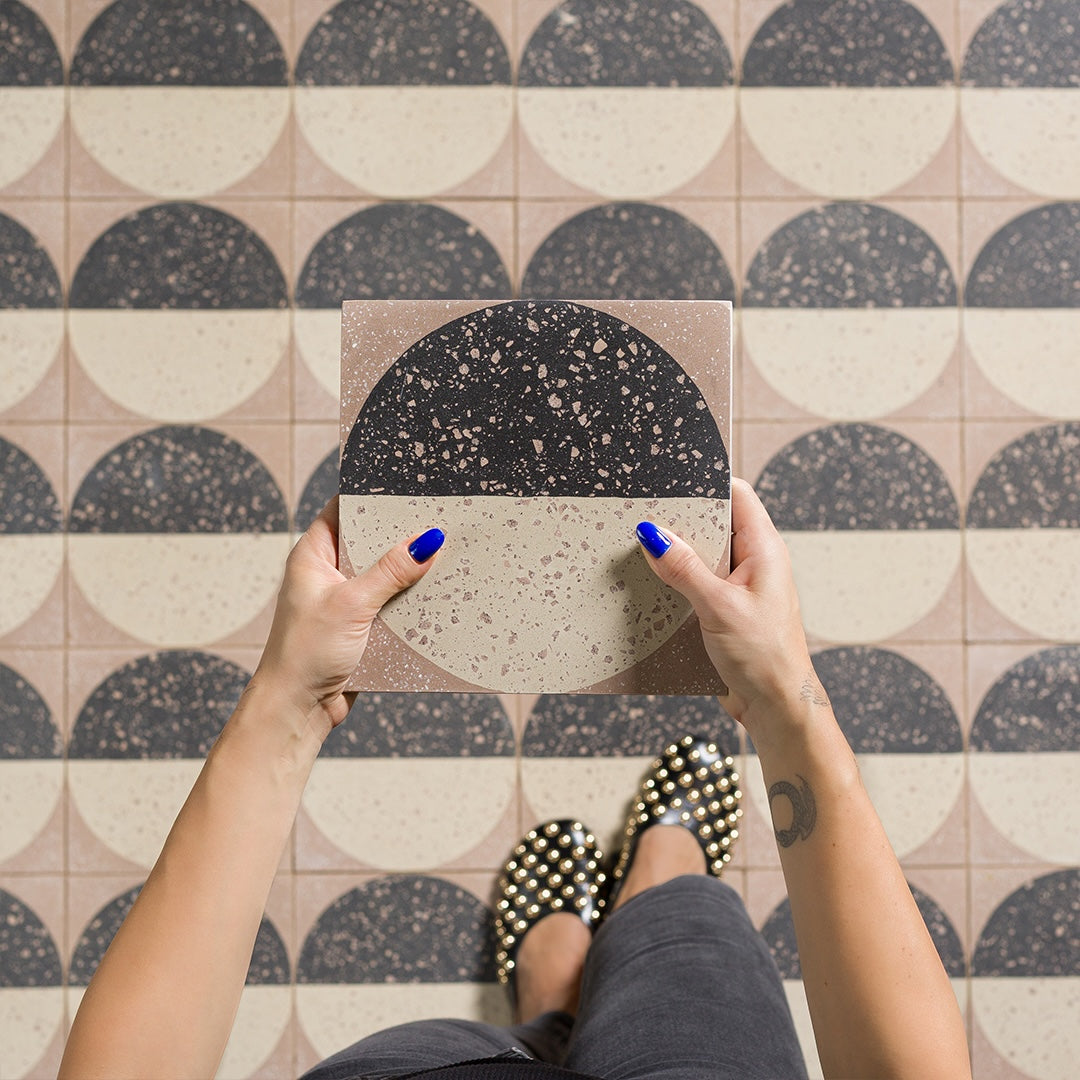 Square cement tile featuring a geometric terrazzo design with a half-black and half-beige circular pattern, showcasing speckled stone textures for modern flooring and wall décor applications.
