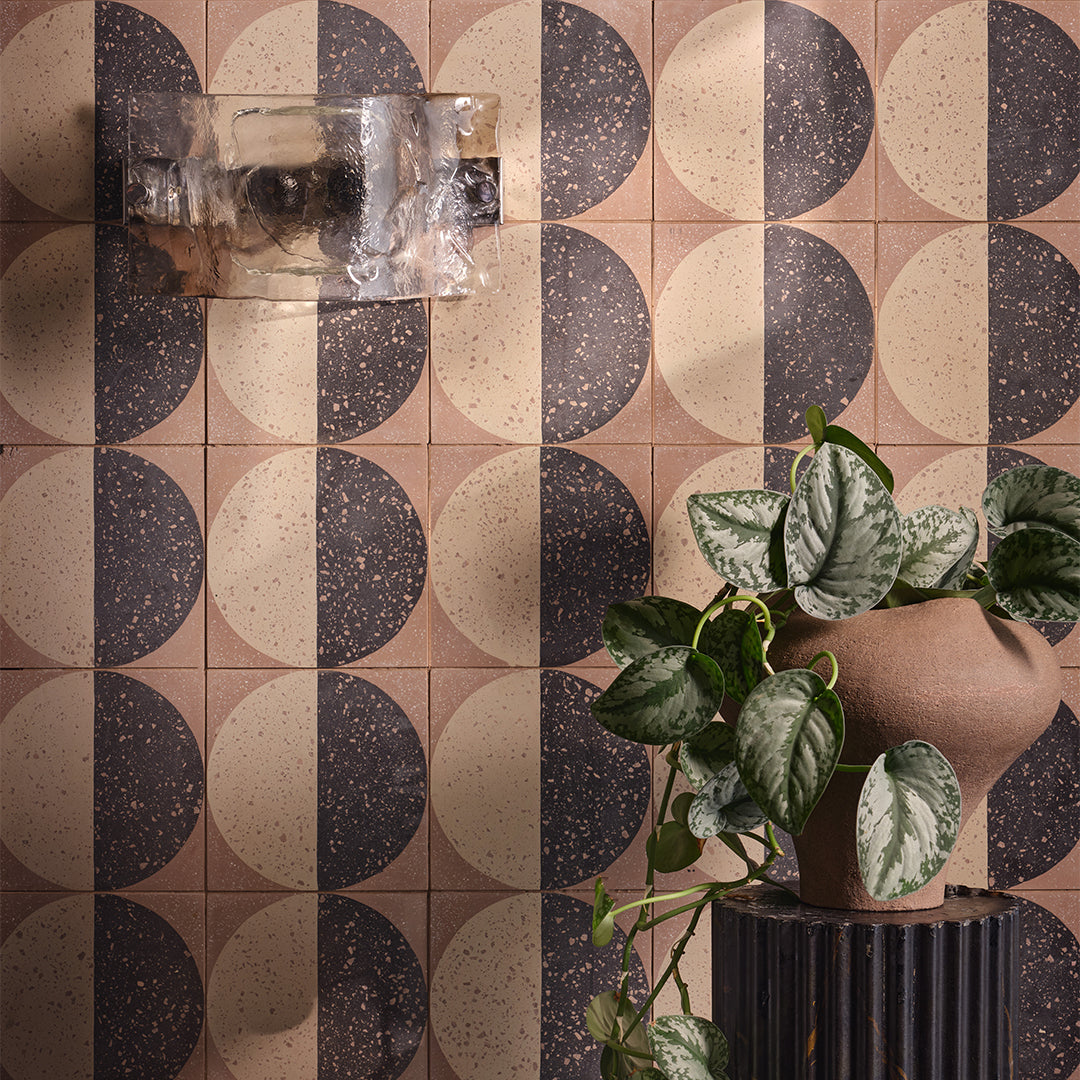 Square cement tile featuring a geometric terrazzo design with a half-black and half-beige circular pattern, showcasing speckled stone textures for modern flooring and wall décor applications.