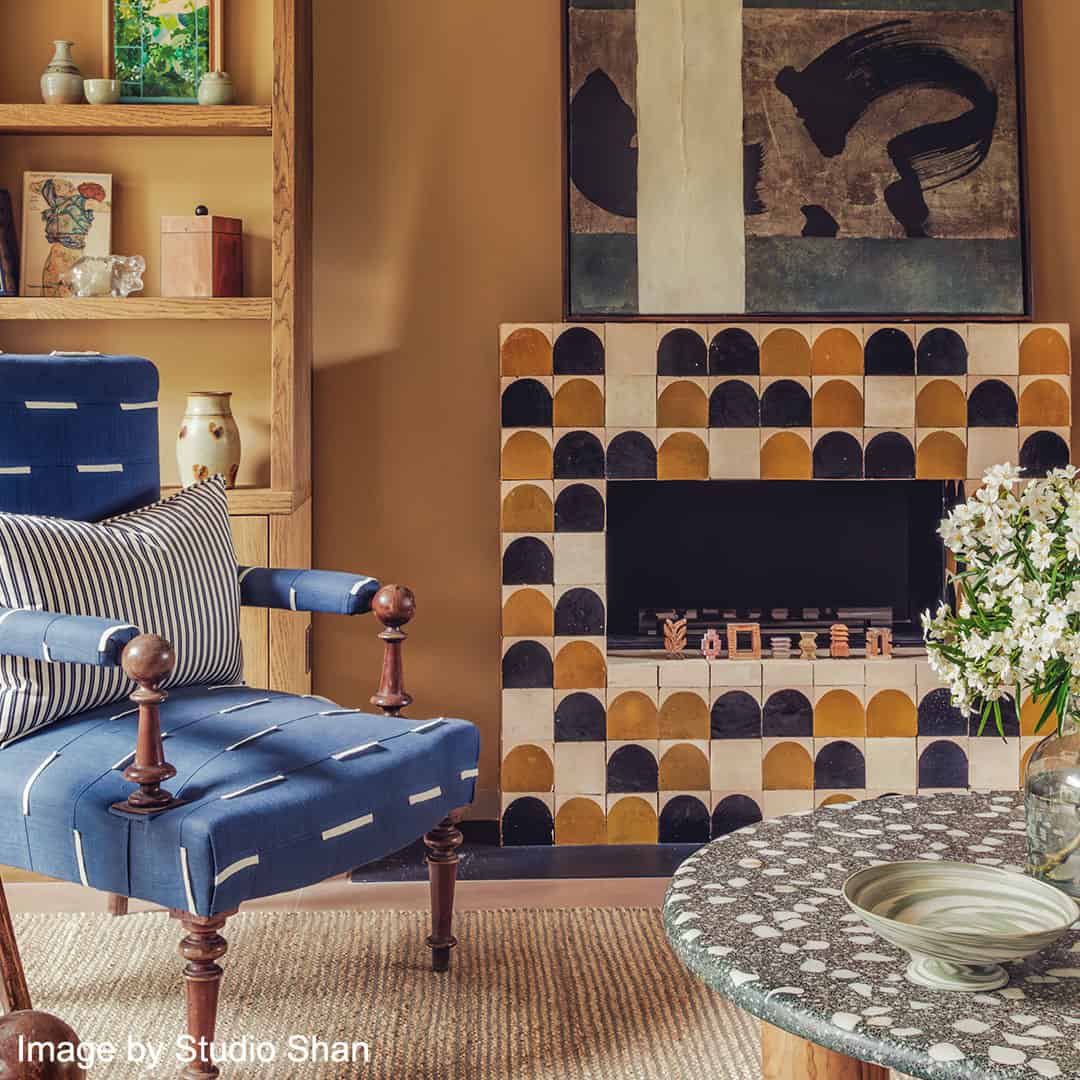A stylish living space with a fireplace decorated in geometric tiles of black, mustard yellow, and cream semicircles. 