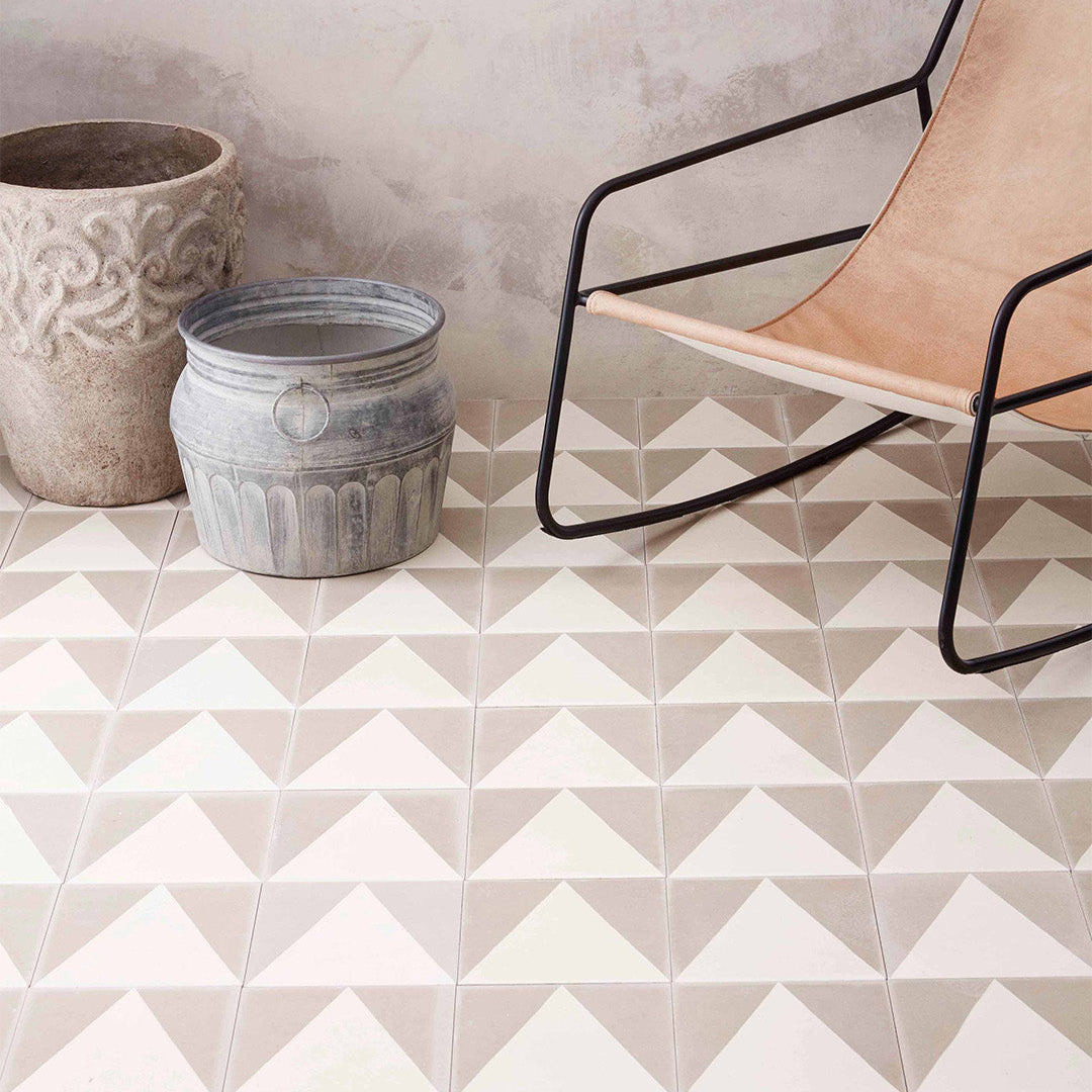 Geometric tile pattern on a floor with a chair and pots in the background