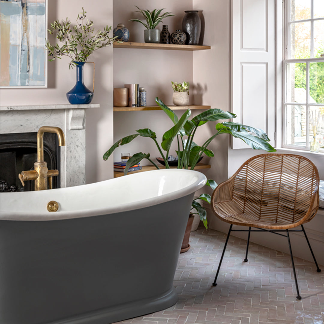 Modern bathroom with freestanding bathtub, wicker chair, and decorative elements.
