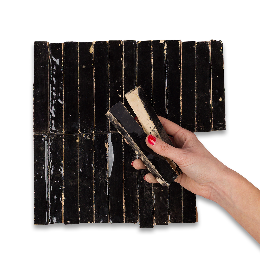 Hand holding a rectangular black tile with a white background