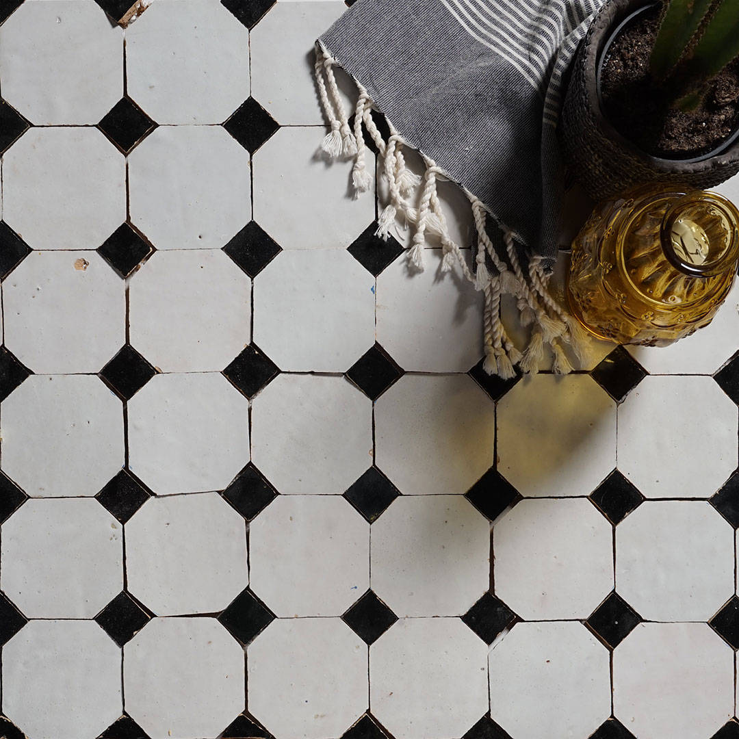 White octagonal tiles with black accents, striped fabric, plant pot, and yellow glass bottle.