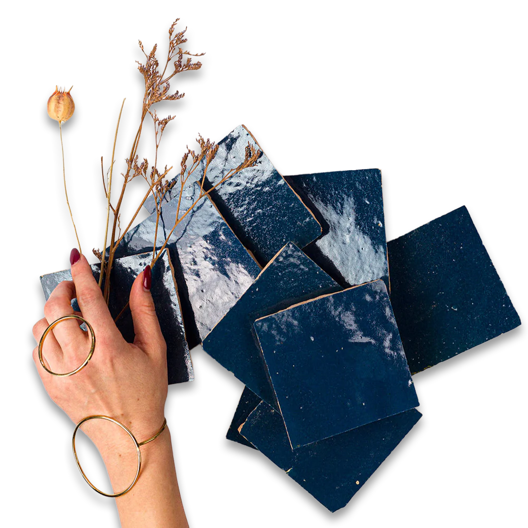 Hand holding a stack of dark blue square tiles with a white background