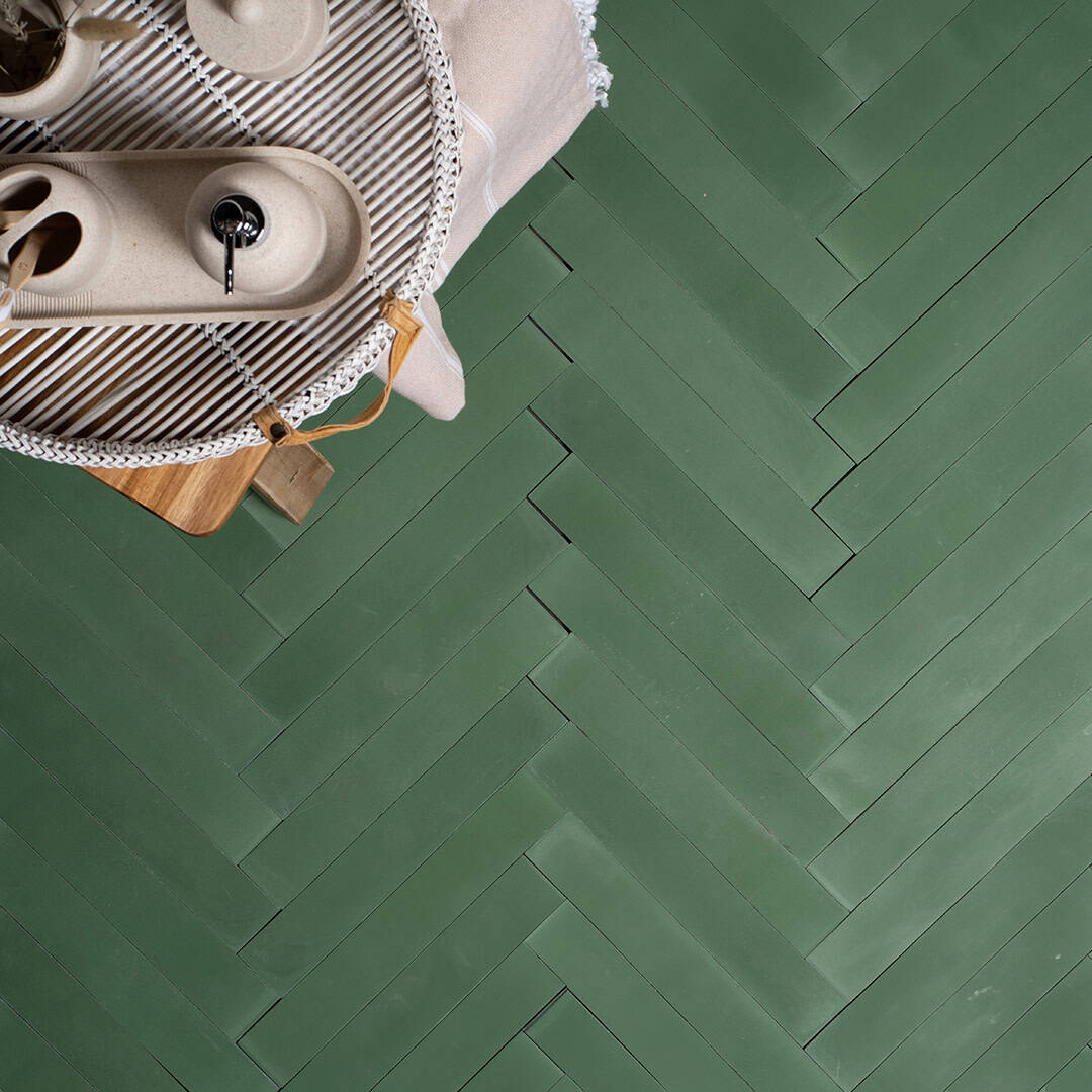 Rectangular cement tiles arranged in a herringbone pattern, forming a chevron-like geometric design that adds texture, symmetry, and visual interest to flooring or wall surfaces.