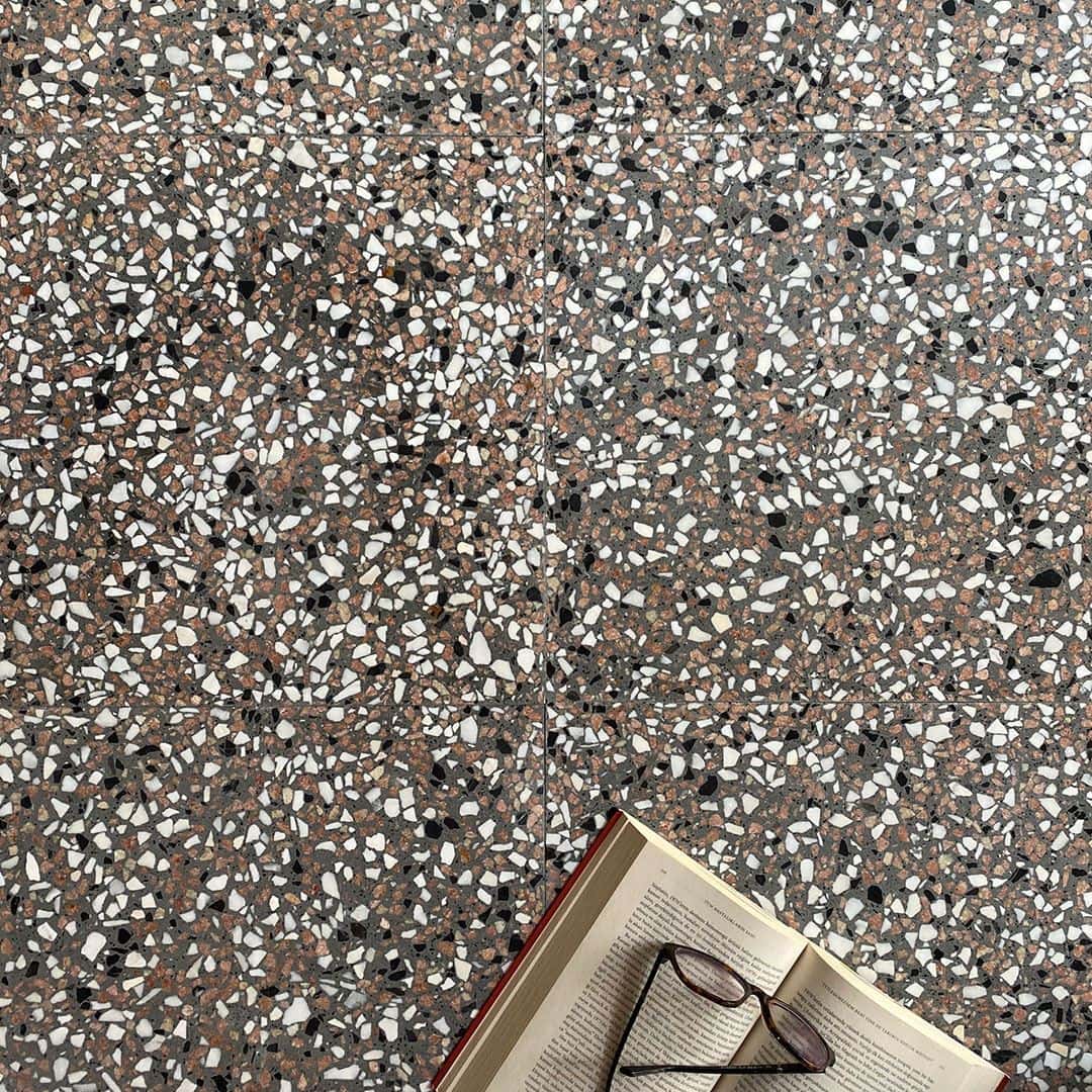 Gray terrazzo tile flooring with multicolor stone chips with an open book and glasses in the side. 